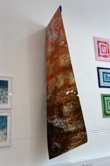 Image of Infinitely Fragile, a large handprinted loop, with cut out sections and gold leaf, as exhibited at Brixton Library 2026.